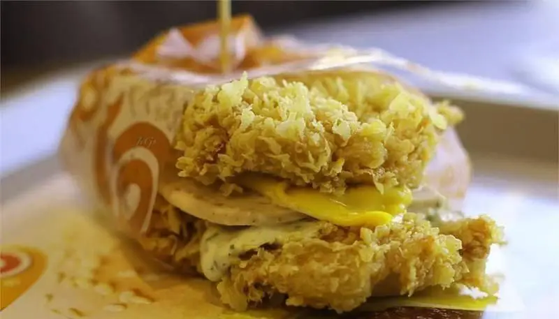 ساندویچ مرغ سوخاری آمادو با پنیر ذوب شده و سس مخصوص، یک انتخاب خوشمزه از منوی فست فود آمادو. مناسب برای تبلیغات رستوران آمادو.