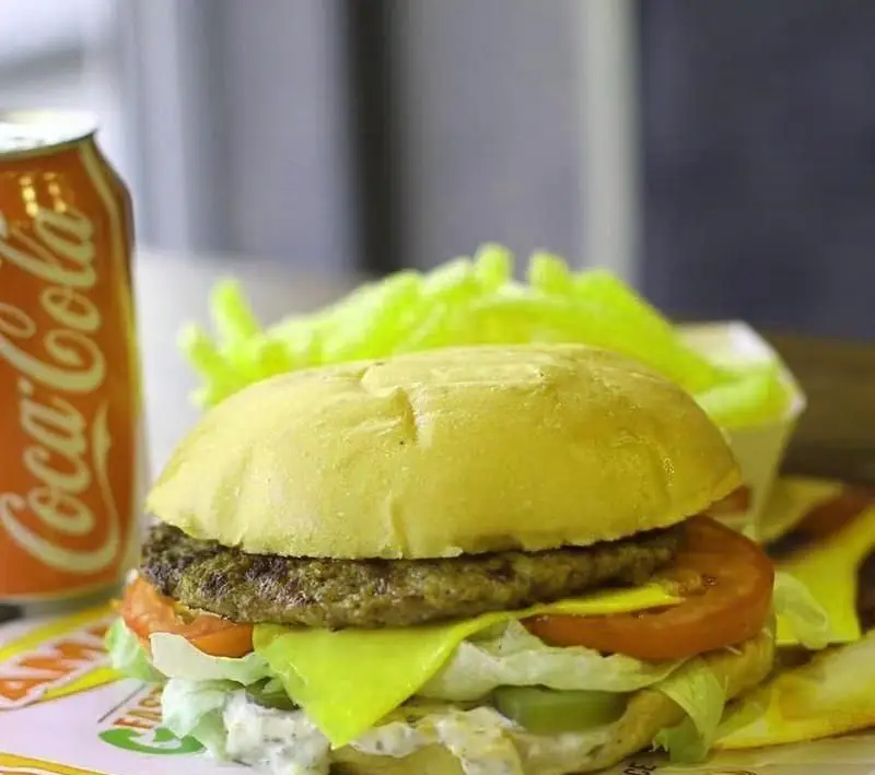 همبرگر خوشمزه فست فود آمادو با پنیر، کاهو، گوجه و خیارشور در کنار سیب زمینی سرخ کرده و نوشابه کوکاکولا.