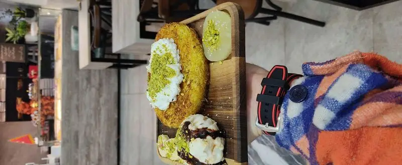 لذت دسر کنافه با خامه و پسته، بستنی شکلاتی و میوه در باقلوا علی کیپا پاسداران. تجربه طعم های اصیل و خاص.