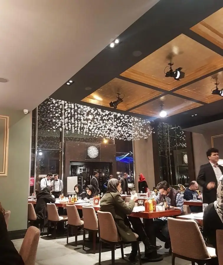 نمایی از داخل کافه و رستوران ایتالیایی سنسو، با سقف طلایی، نورپردازی خاص و مشتریانی که در حال صرف غذا در محیطی دلنشین هستند.