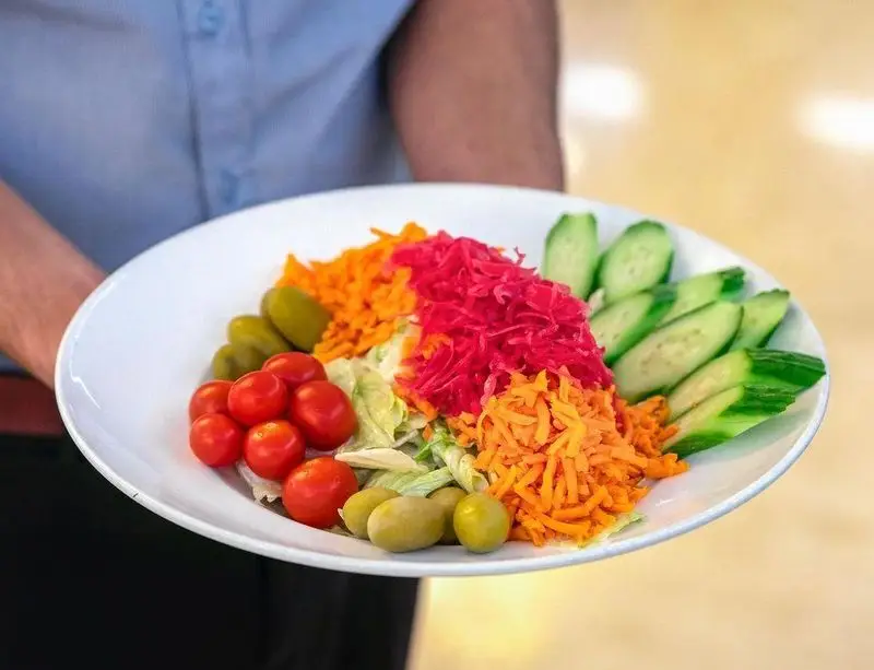 بشقاب سالاد رنگارنگ رستوران محسن شامل سبزیجات تازه نظیر خیار، هویج، گوجه گیلاسی، زیتون و انواع ترشی.