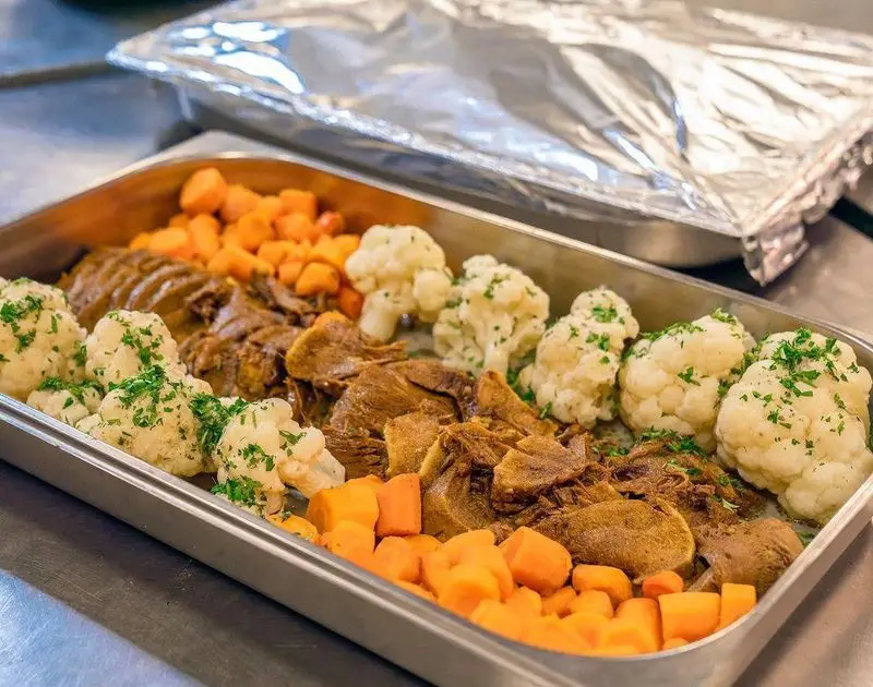 سینی غذای آماده و باکیفیت رستوران محسن شامل خوراک گوشت پخته، هویج و گل کلم تازه برای پذیرایی از مهمانی‌ها.