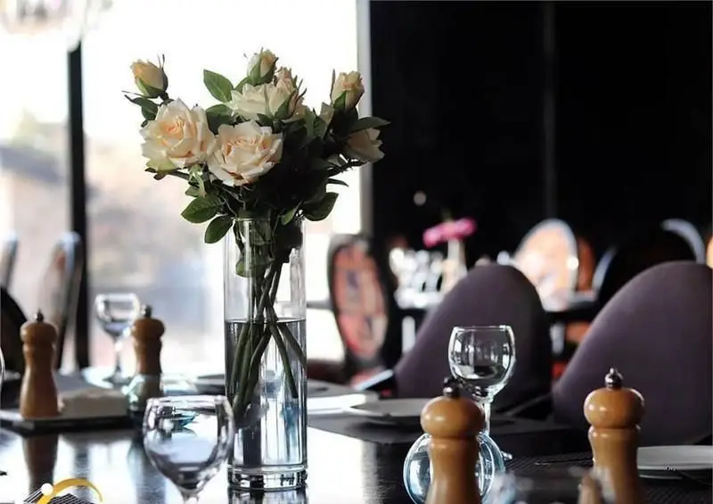 فضای لوکس و دکوراسیون شیک رستوران فرنگی وی آی پی سورینت، با میز آرایی دلنشین شامل گلدان گل رز و آماده برای مهمانان خاص.