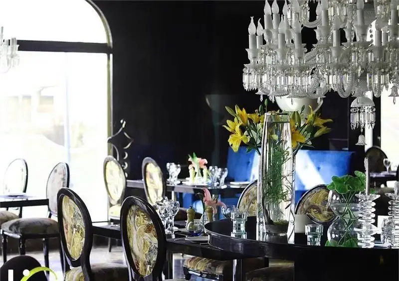 نمایی از فضای داخلی رستوران فرنگی وی آی پی سورینت، دارای لوستر کریستالی بزرگ، میزهای غذاخوری مشکی و صندلی‌های مجلل با طرح‌های زیبا.