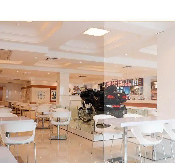 محیط داخلی روشن و مدرن رستوران فرنگی وی آی پی سورینت با طراحی شیک، میز و صندلی‌های سفید و موتورسیکلتی چشمگیر.
