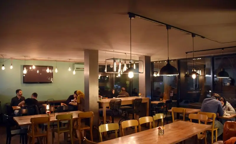 فضای داخلی دنج رستوران سبوس با نورپردازی دلنشین، میزهای چوبی و مشتریان. محیطی گرم و مناسب برای تجربه غذایی لذت‌بخش.