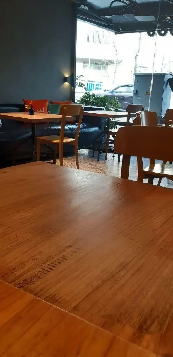 فضای داخلی دنج و مدرن رستوران سبوس با میز و صندلی‌های چوبی، مبلمان راحتی و منظره زیبای خیابان، ایده‌آل برای یک تجربه لذت‌بخش.