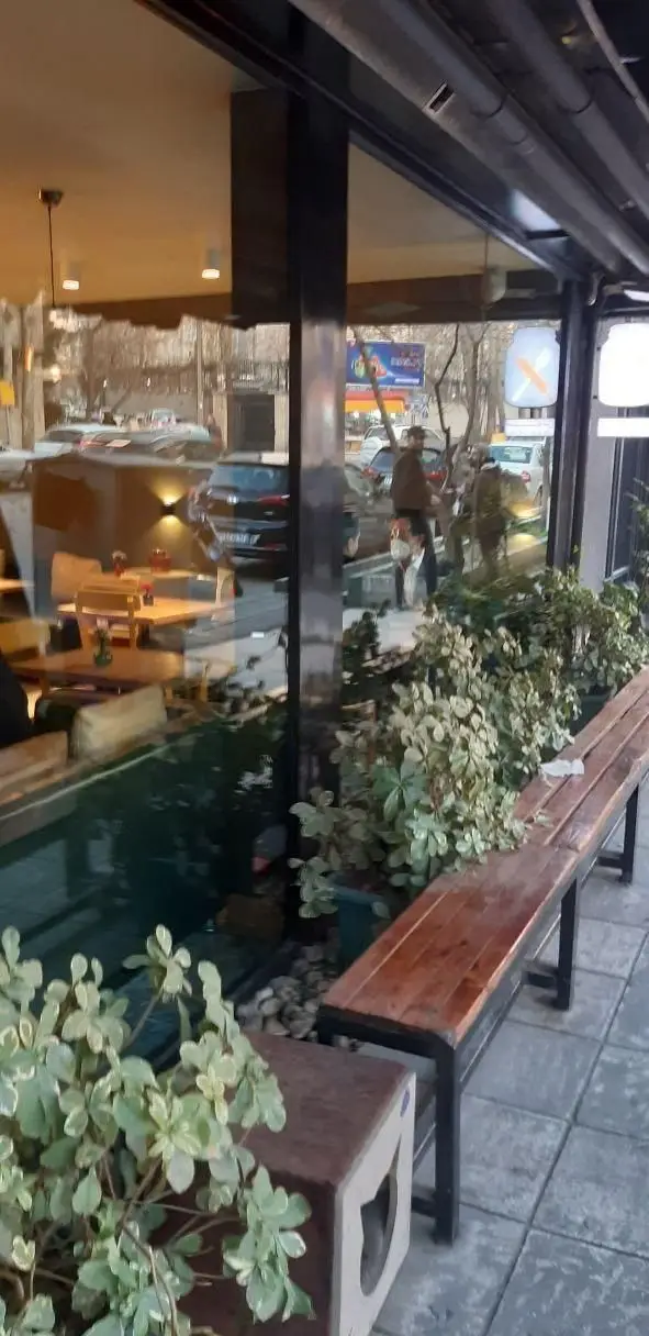 نمای بیرونی جذاب رستوران سبوس، با پنجره‌های شیشه‌ای بزرگ، فضای داخلی دلنشین و میز و صندلی و فضای سبز در پیاده‌رو.