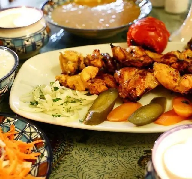 سفره خانه سنتی باغ فردوس: جوجه کباب لذیذ با گوجه کبابی، پیاز، ترشی و دورچین در محیط سنتی رستوران ایرانی.