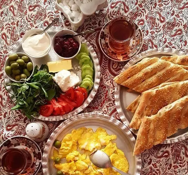 صبحانه سنتی ایرانی در سفره خانه باغ فردوس شامل نان تازه، املت، پنیر، کره، مربا، سبزی، زیتون، گوجه، خیار و چای معطر.