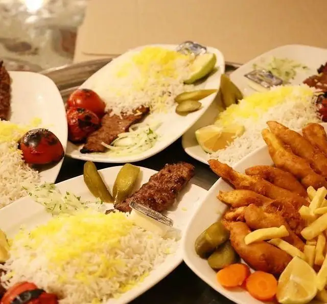 انواع چلوکباب کوبیده و برگ با برنج زعفرانی، گوجه کبابی، خیارشور، ماهی سوخاری و سیب زمینی سرخ کرده در سفره خانه سنتی باغ فردوس.