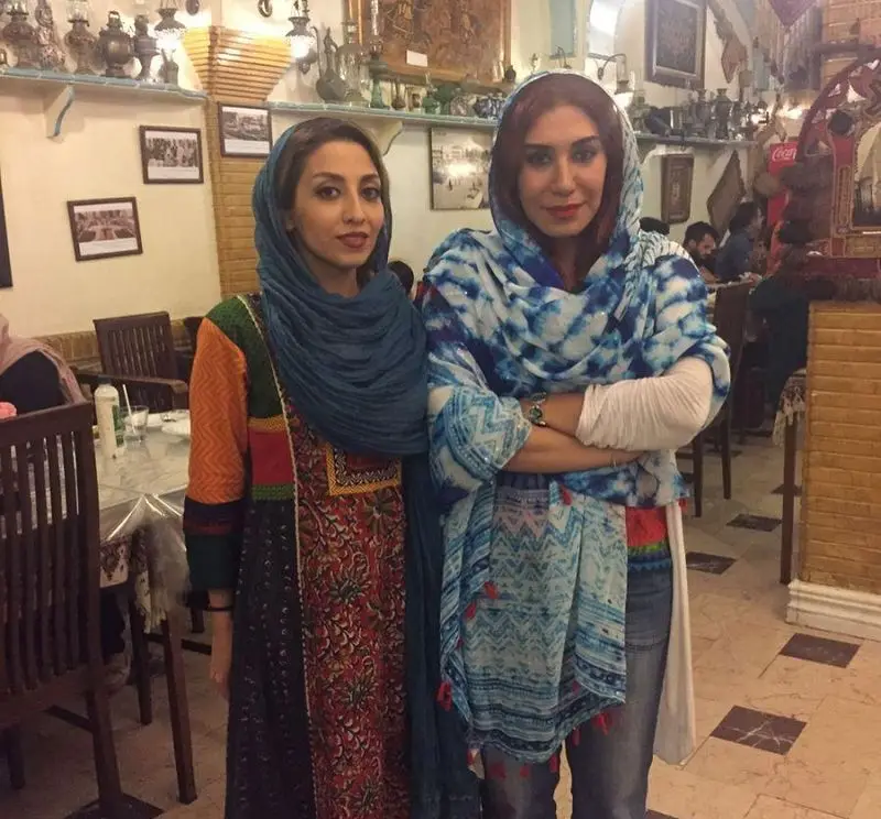 دو خانم در فضای سنتی سفره خانه سنتی باغ فردوس با دکوراسیون زیبا و مشتریان دیگر. تجربه ای دلنشین در رستوران سنتی.