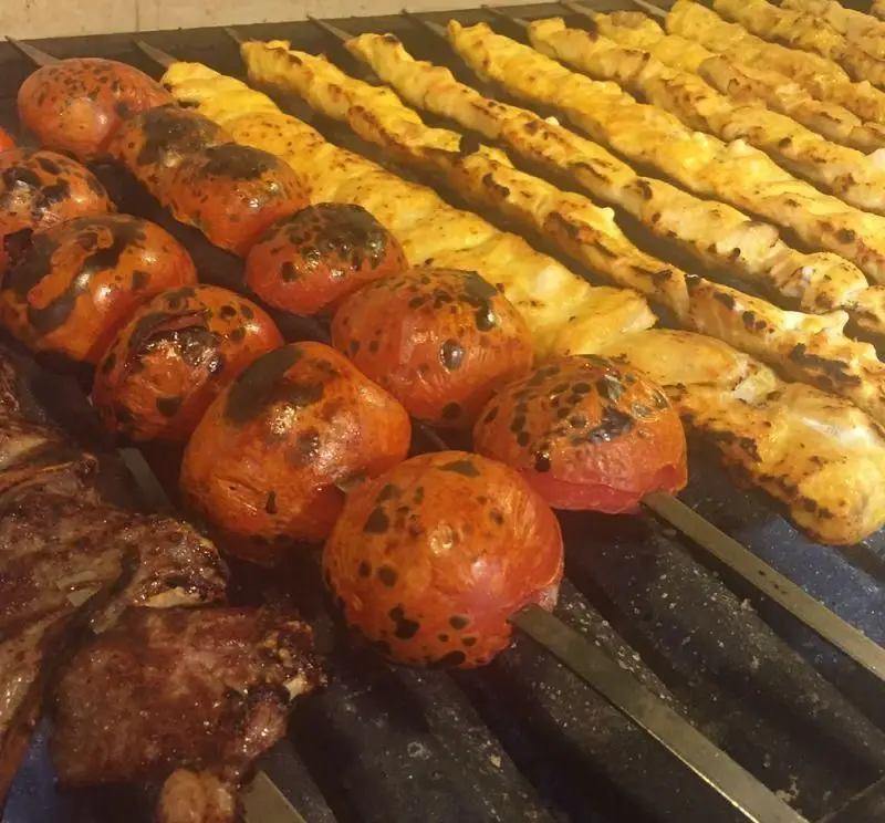 لذت تجربه غذای ایرانی اصیل در سفره خانه سنتی باغ فردوس: کباب‌های لذیذ جوجه، گوشت و گوجه کبابی تازه روی منقل.