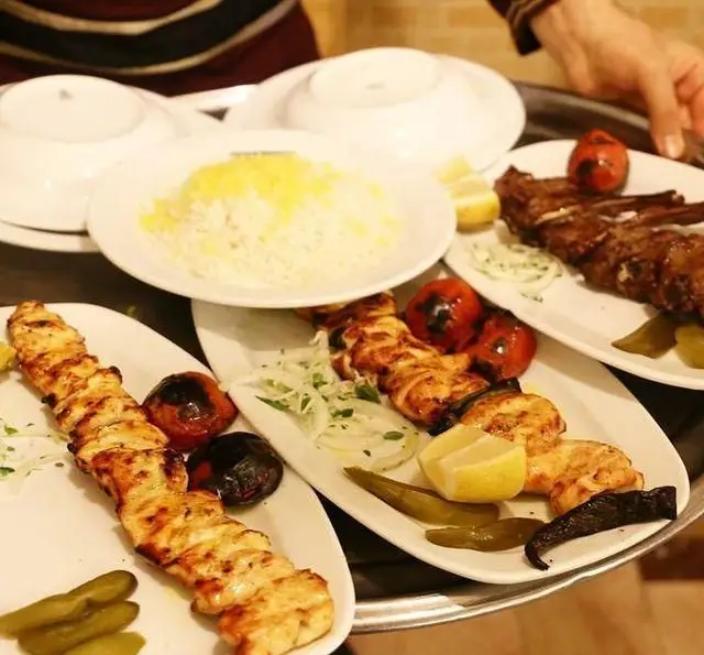 تصویری از سینی غذای سفره خانه سنتی باغ فردوس شامل چلو کباب، جوجه کباب، شیشلیک، برنج، گوجه و مخلفات لذیذ ایرانی.