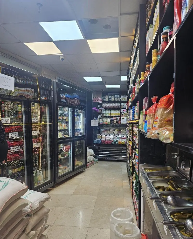 راهروی داخلی و تمیز فروشگاه فست فود رسپینا با قفسه‌های پر از محصولات غذایی، نوشیدنی‌ها، ترشیجات و انبار برنج مشتریان.