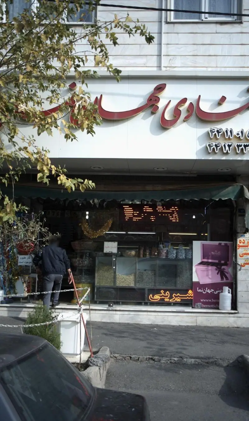 سردر اصلی و نمای فروشگاه قنادی جهان نما، شامل تابلو و ویترین‌های پر از آجیل، خشکبار و شیرینی‌های تازه.