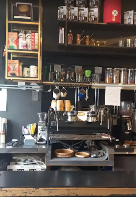 دکوراسیون شیک کافه امیر با دستگاه اسپرسو پیشرفته، آسیاب قهوه، قفسه‌های محصولات و لوازم جانبی متنوع برای عاشقان قهوه.