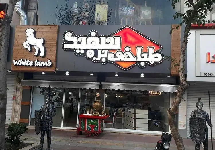 عکس تابلوی طباخی بره سفید با لوگوی گوسفند سفید، ارائه دهنده کله پاچه و غذاهای سنتی لذیذ در محیطی دلنشین.