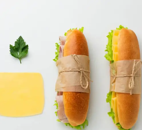 دو ساندویچ لقمه‌ای هایدا: یکی با ژامبون و کاهو، دیگری با پنیر و کاهو، همراه با پنیر ورقه و جعفری، مناسب ناهار.