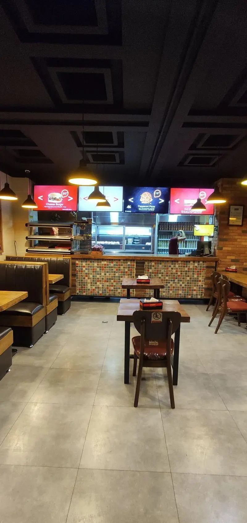 فضای داخلی مدرن رستوران فست فود ساندویچ هایدا با میز و صندلی چوبی، پیشخوان موزاییکی، منوهای دیجیتال جذاب.