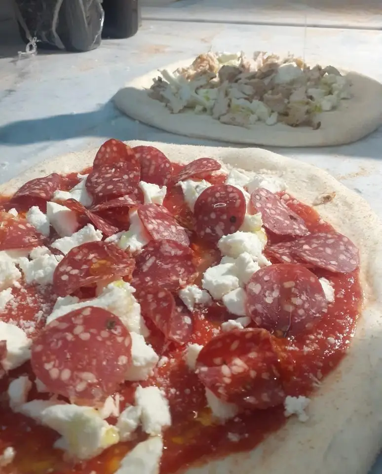 پیتزاهای دست‌ساز در حال آماده‌سازی در رستوران فرسکو: پیتزا پپرونی با پنیر تازه و سس گوجه، و پیتزایی دیگر با مواد خاص.