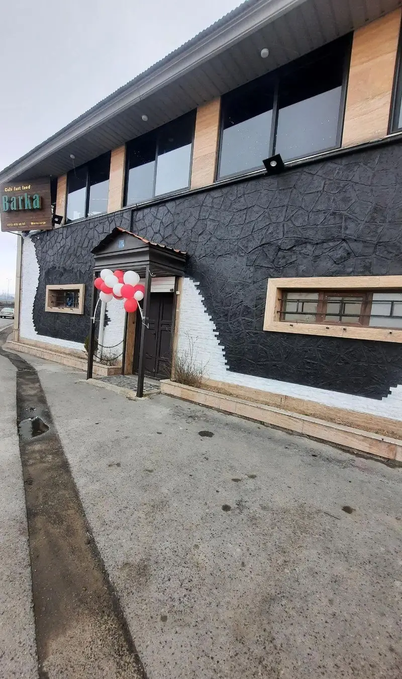 نمای بیرونی کافه فست فود بارکا با دیوارهای مشکی طرح‌دار، پنجره‌های بزرگ و ورودی تزیین شده با بادکنک‌های قرمز و سفید.