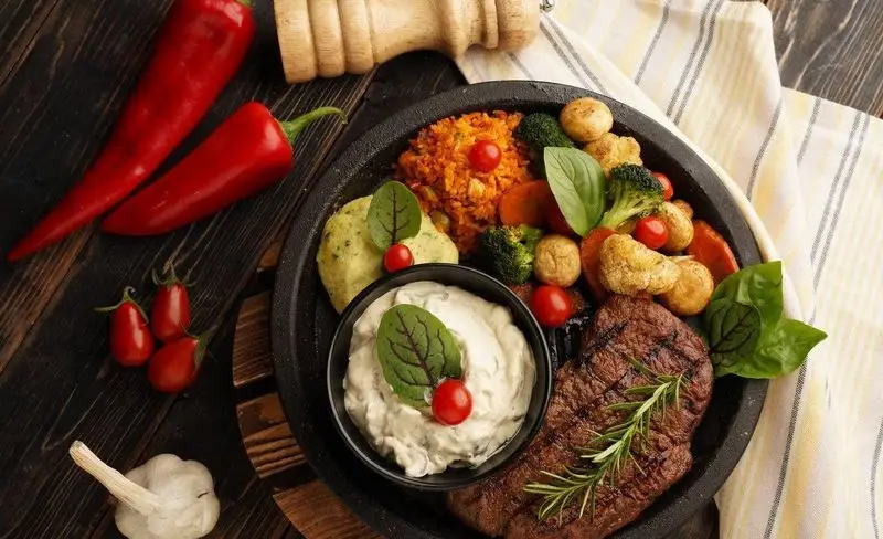 یک بشقاب غذای کامل و لذیذ از فست فود د ل پ: استیک گریل شده با رزماری، پوره، برنج، بروکلی، قارچ، هویج و گوجه گیلاسی با سس.