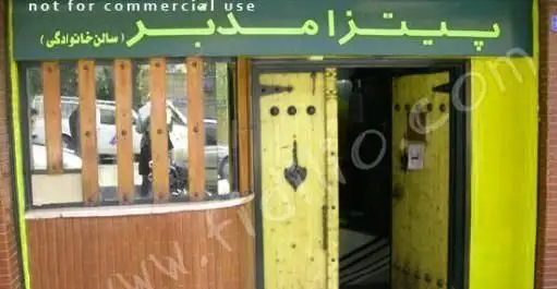 تصویر نمای بیرونی رستوران پیتزا مدبر با درب ورودی زرد رنگ و پنجره چوبی. این پیتزافروشی دارای سالن خانوادگی است.