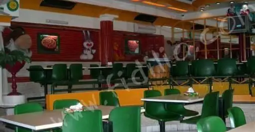 نمای داخلی فست فود پیتزا مدبر، با چیدمان صندلی‌های سبز و میزهای سفید، دکوراسیون رنگارنگ و محیطی دلنشین برای صرف پیتزا.