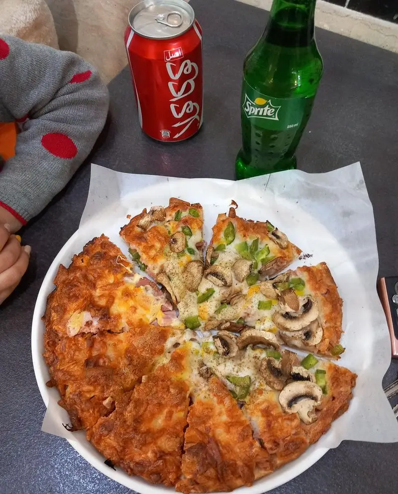 پیتزای خوشمزه و تازه از فستفود گل رز با دو طعم قارچ و فلفل دلمه ای، همراه با نوشابه کوکا و اسپرایت برای یک وعده عالی.