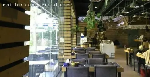 فضای داخلی رستوران ایرانی ته دیگ با دکوراسیون چوبی مدرن، میز و صندلی‌های شیک و چشم‌انداز دلنشین به فضای سبز.