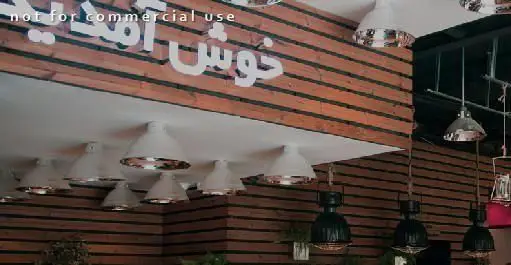 دکوراسیون جذاب و مدرن رستوران ایرانی ته دیگ، با دیوارهای چوبی طرح‌دار، سقف سفید، چراغ‌های آویز شیک و تابلوی "خوش آمدید".