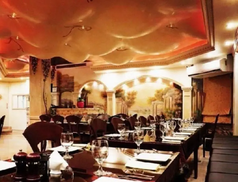 فضای داخلی شیک رستوران فرنگی ایرمان با میزهای چیده شده، سقف دکوراتیو و نقاشی دیواری زیبا، محیطی دلنشین برای مشتریان.