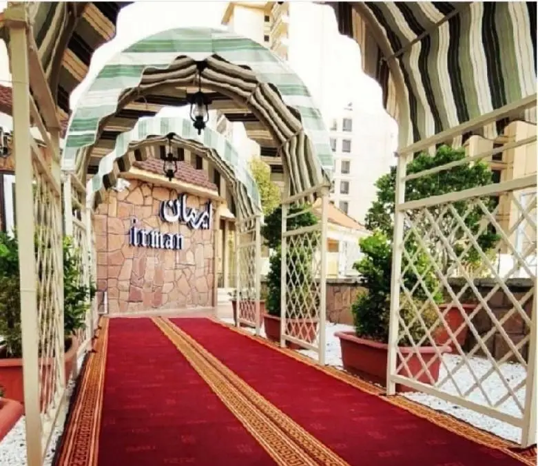 ورودی دلنشین و شیک رستوران فرنگی ایرمان با فرش قرمز پهن شده، سقف سایبان‌دار راه راه، و دیوارهای سنگی با نام "ایرمان".