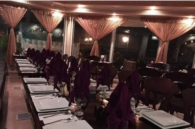فضای داخلی رستوران فرنگی ایرمان، با میزهای چیده شده شیک، بشقاب‌های سفید و دستمال‌های بنفش. آماده پذیرایی در محیطی لوکس و دلنشین.