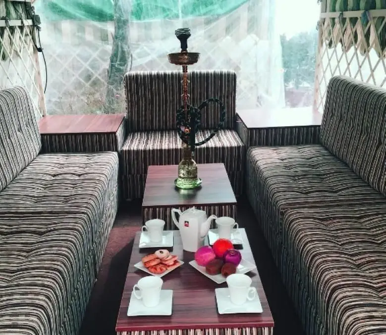 رستوران فرنگی ایرمان: فضای نشیمن راحت با مبلمان راه راه، میزهای چوبی، قلیان، سرو چای و دسر. محیطی آرام و دلپذیر.