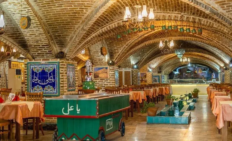 رستوران سنتی ترمه با فضای داخلی دلنشین، سقف‌های آجری قوسی، میز و صندلی چوبی، آبنمای زیبا و دکوراسیون سنتی ایرانی.