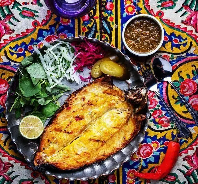 ماهی کبابی سنتی رستوران ترمه با سبزی تازه، پیاز، ترشی و لیمو. طعم اصیل غذای ایرانی در فضایی دلنشین و رنگارنگ.