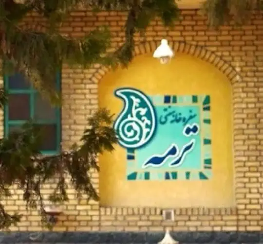 تابلوی زیبای رستوران سنتی ترمه با نقش بته جقه و رنگ‌های دلنشین، بر دیوار آجری ساختمانی با معماری اصیل ایرانی؛ تجربه غذای سنتی.