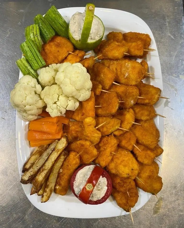 سینی پربار کترینگ لاوان: فیله مرغ سوخاری، سیب زمینی سرخ کرده، گل کلم و هویج بخارپز، سبزیجات تازه با دیپ سس لذیذ.