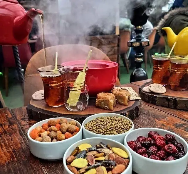 دورهمی دلنشین در کافه چوب سبز با چای داغ، نبات، باقلوا، آجیل و تنقلات متنوع. فضایی گرم و سنتی برای عصرانه.