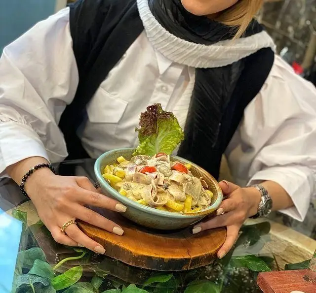 تصویری دلپذیر از غذای خاص کافه چوب سبز: سیب زمینی با سس قارچ و مرغ، که در محیطی آرام و سرسبز کافه سرو می‌شود.