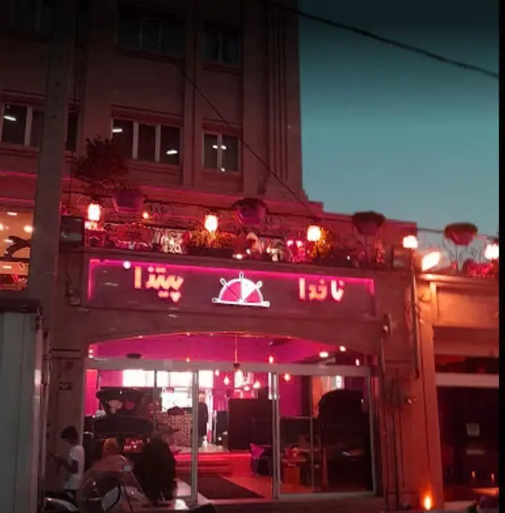 ورودی چشم نواز پیتزا ناخدا با نورپردازی صورتی و طراحی داخلی مدرن. بهترین فست فود برای تجربه طعم لذیذ پیتزا در شب.