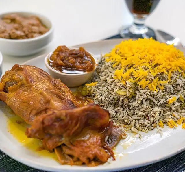 تصویری جذاب از باقالی پلو با ماهیچه گوسفندی در کنار سس مخصوص و برنج زعفرانی، یکی از غذاهای محبوب رستوران محسن.