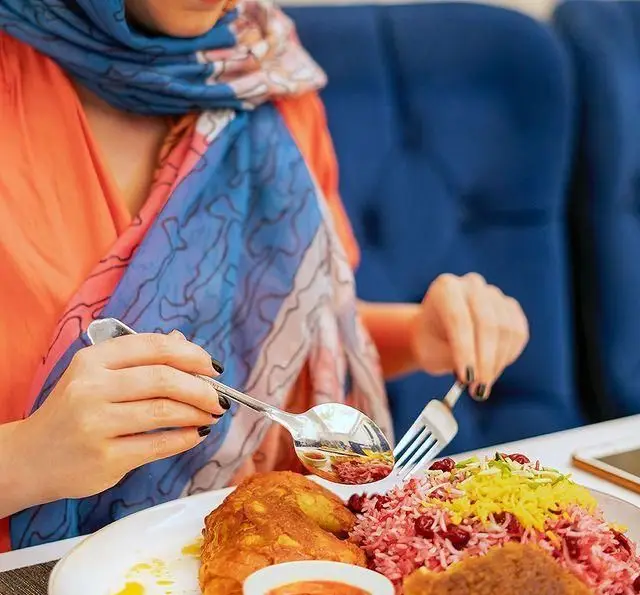مشتری در رستوران محسن در حال میل کردن غذای ایرانی لذیذ (مانند زرشک پلو با مرغ). تجربه‌ای دلنشین از کیفیت و طعم عالی.