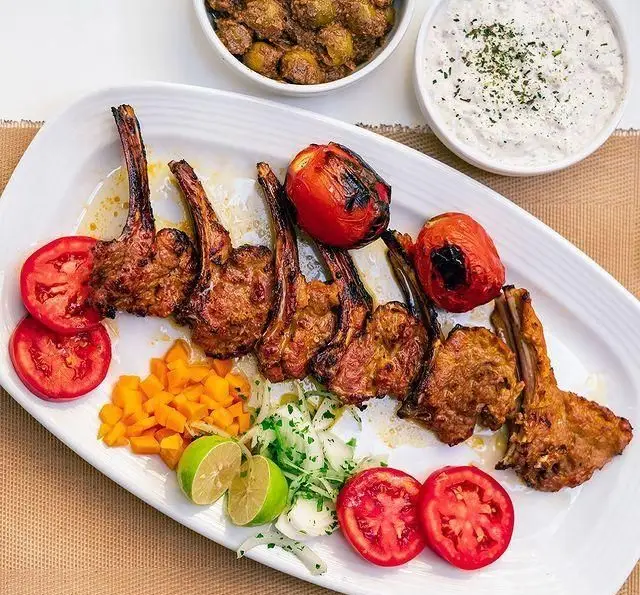 تصویر جذاب شیشلیک و دنده کباب ویژه رستوران محسن، با گوجه کبابی، لیمو تازه، پیاز، سبزیجات و ماست. بهترین کباب ایرانی.