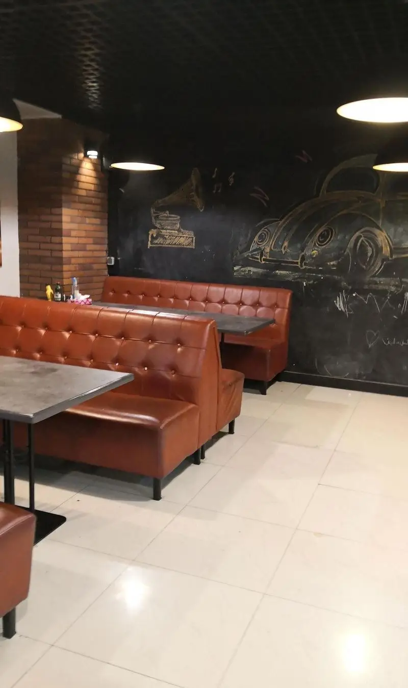 فضای داخلی مدرن و دنج رستوران بیگ بنگ، با نیمکت‌های چرمی راحت، میزهای شیک و دیوار گچی با نقاشی‌های جذاب وینتج.