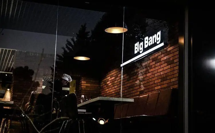 رستوران بیگ بنگ در شب با نمای داخلی آجری، مبلمان شیک، نورپردازی گرم و تابلوی درخشان. تجربه‌ای دلنشین از غذا در محیطی مدرن.