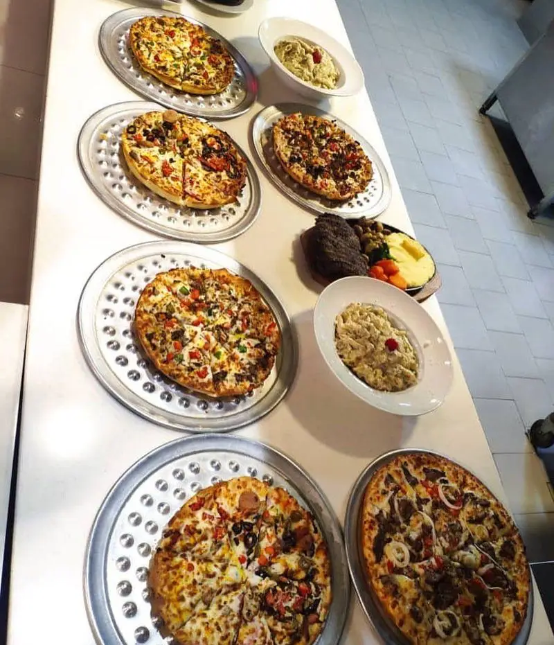 میز غذای رنگارنگ با پیتزاهای متنوع، پاستای خامه‌ای و استیک آبدار در رستوران بیگ بنگ، تجربه‌ای دلپذیر از طعم‌ها.