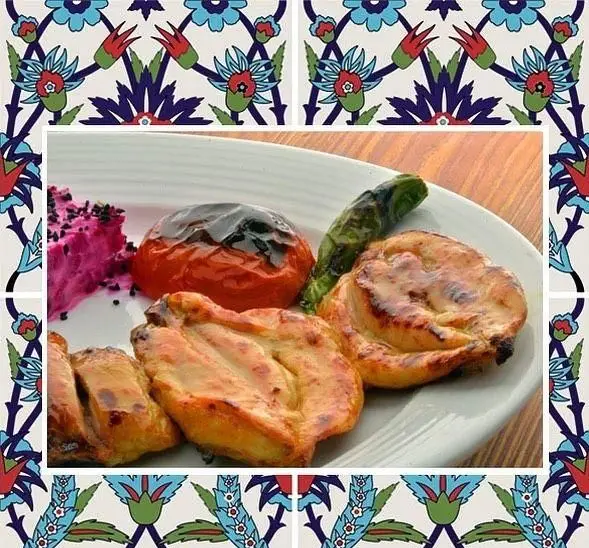 یک بشقاب کباب مرغ آبدار با گوجه و فلفل کبابی، همراه مخلفات صورتی، از رستوران باغ طهرون، با قاب کاشی‌کاری سنتی ایرانی.